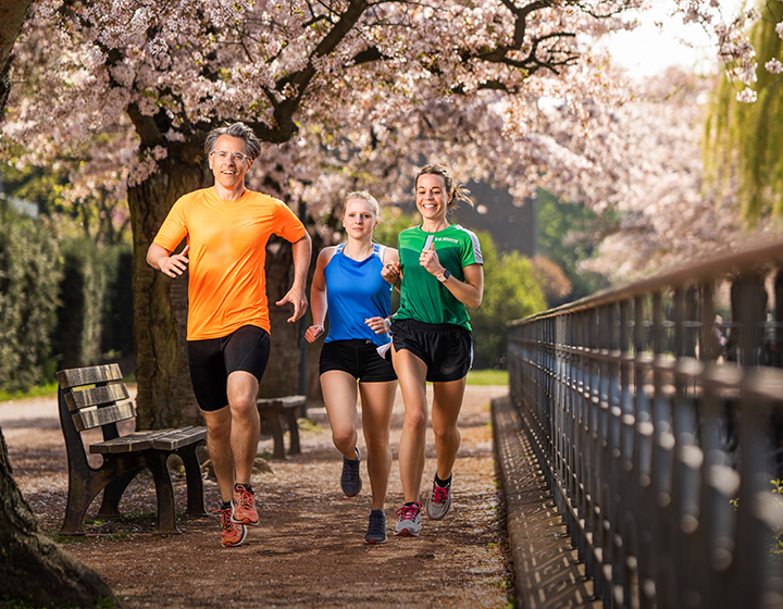 3 Leute beim Joggen durch Kirschblüten-Allee